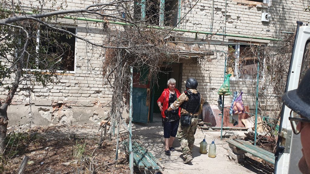 Woman in red coming out of bombed house in Bakhmut
