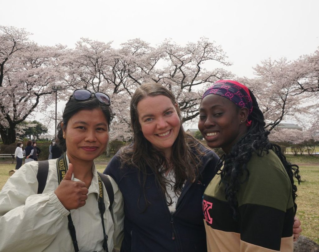 Photo of rebecca boardman and two other young women in front of a cherry blossom tree
